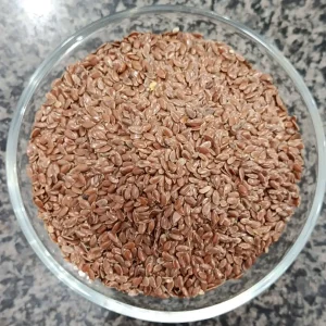 Whole brown flax seeds in a glass bowl — السی کے بیج